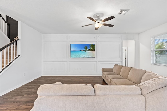 living room with visible vents, baseboards, ceiling fan, dark wood-style floors, and stairway