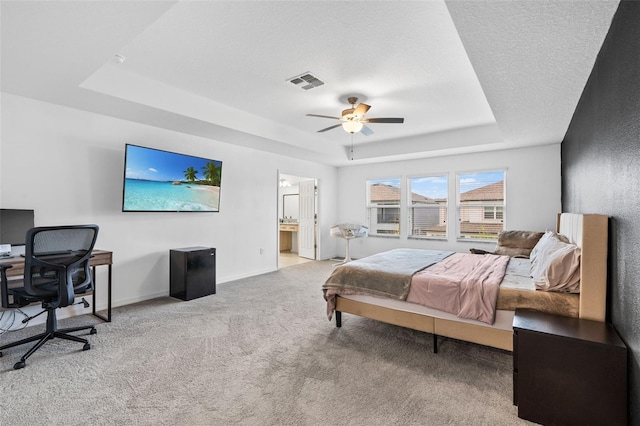 bedroom with baseboards, ensuite bathroom, carpet floors, visible vents, and a raised ceiling