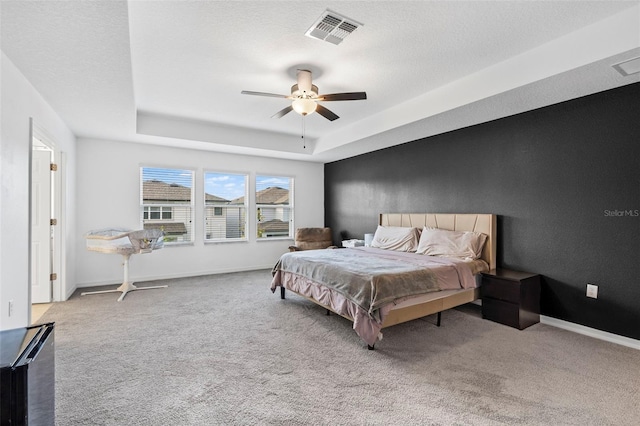 carpeted bedroom with visible vents, baseboards, a tray ceiling, and ceiling fan