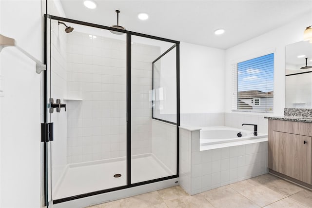 bathroom with a stall shower, a garden tub, vanity, and recessed lighting