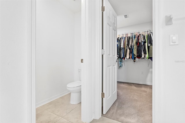 bathroom with tile patterned flooring, baseboards, and toilet