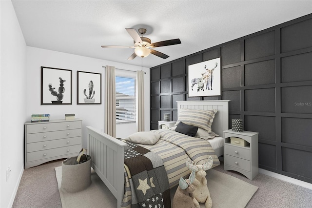 bedroom with a decorative wall, baseboards, ceiling fan, and light colored carpet