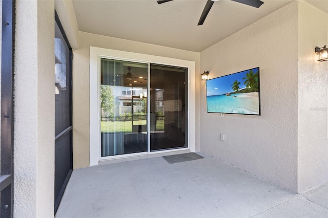 entrance to property with ceiling fan, stucco siding, and a patio area