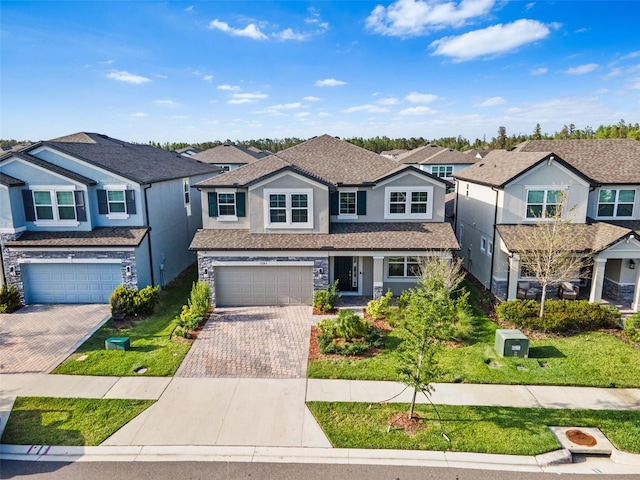 traditional-style home featuring stucco siding, decorative driveway, stone siding, an attached garage, and a residential view
