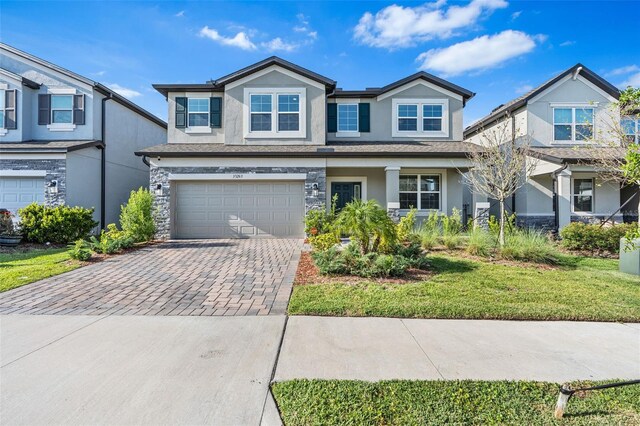 craftsman-style home featuring an attached garage, stucco siding, stone siding, and decorative driveway