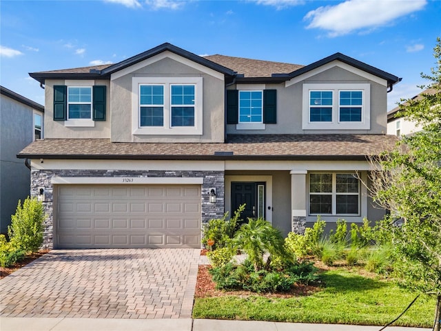 33263 Sycamore Leaf Dr, Wesley Chapel, FL 33545 - craftsman house featuring stucco siding, decorative driveway, a garage, a shingled roof, and stone siding