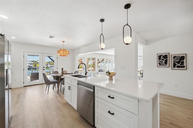 9920 Spoonbill Rd E, Bradenton, FL 34209 - kitchen featuring stainless steel appliances, a sink, french doors, light wood-style flooring, and a textured ceiling