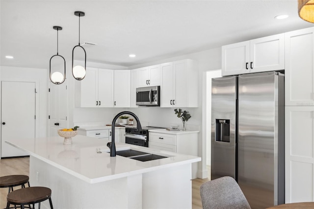 9920 Spoonbill Rd E, Bradenton, FL 34209 - kitchen with appliances with stainless steel finishes, a sink, light wood-style floors, white cabinetry, and a kitchen bar