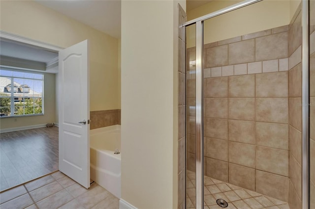 6451 Sunset Bay Cir, Apollo Beach, FL 33572 - bathroom featuring tile patterned flooring, a bath, a stall shower, and baseboards