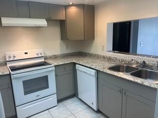 kitchen featuring a sink, white appliances, gray cabinets, light countertops, and under cabinet range hood