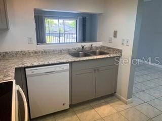 kitchen with stove, dishwasher, gray cabinets, light tile patterned floors, and a sink