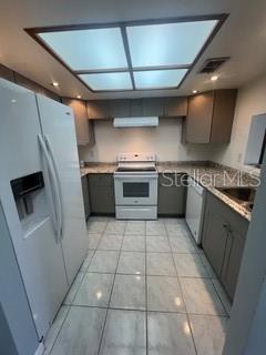 kitchen with white refrigerator with ice dispenser, range with electric stovetop, light tile patterned floors, gray cabinetry, and visible vents