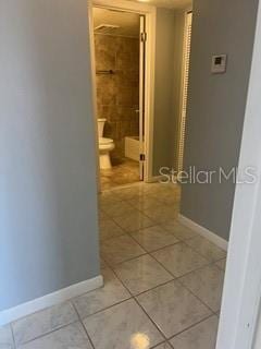 corridor featuring baseboards and light tile patterned floors