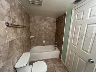 bathroom featuring tile patterned flooring, tub / shower combination, visible vents, and toilet