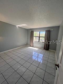 empty room featuring baseboards and light tile patterned floors