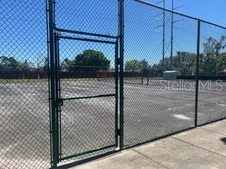 view of tennis court with a gate and fence