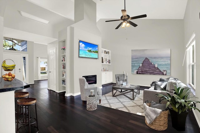 9603 Sunnyoak Dr, Riverview, FL 33569 - living room featuring hardwood / wood-style floors, a glass covered fireplace, built in shelves, ceiling fan, and a towering ceiling