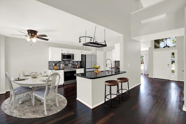 9603 Sunnyoak Dr, Riverview, FL 33569 - kitchen featuring a peninsula, dark countertops, decorative backsplash, dark wood-type flooring, and appliances with stainless steel finishes