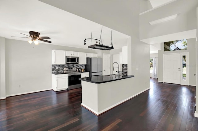 9603 Sunnyoak Dr, Riverview, FL 33569 - kitchen with dark countertops, white cabinets, decorative backsplash, dark wood finished floors, and appliances with stainless steel finishes