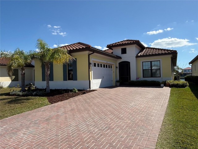 mediterranean / spanish-style house featuring decorative driveway, stucco siding, an attached garage, and a tile roof