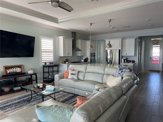 living room with ceiling fan, crown molding, baseboards, a textured ceiling, and dark wood finished floors