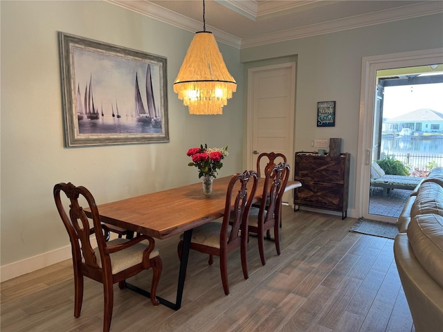dining area featuring wood finished floors, crown molding, a chandelier, and baseboards