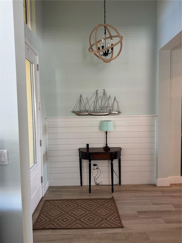 corridor with a chandelier, wood finished floors, and a wainscoted wall