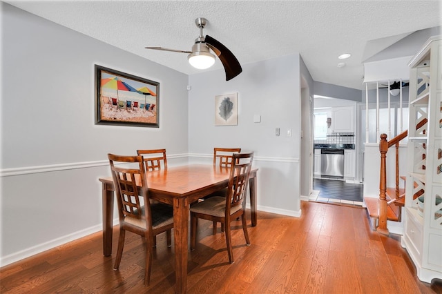 dining room with a ceiling fan, baseboards, a textured ceiling, and light wood-style flooring