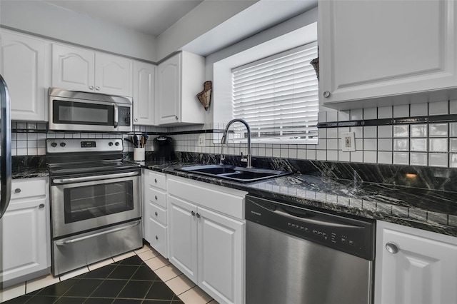 kitchen featuring a sink, decorative backsplash, stainless steel appliances, white cabinets, and tile patterned flooring