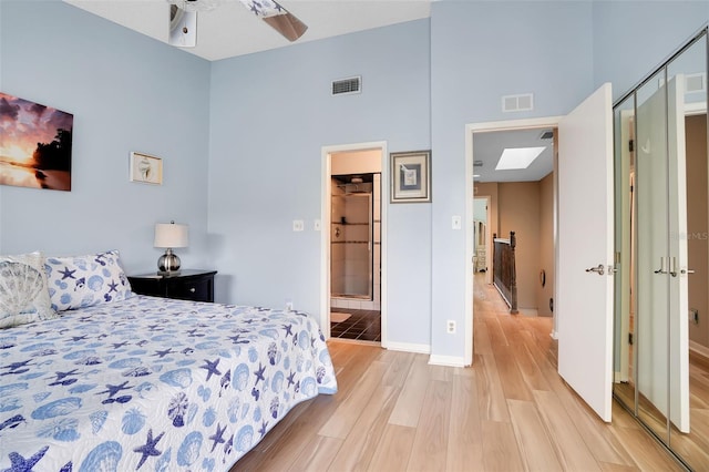 bedroom featuring a high ceiling, baseboards, visible vents, and light wood-style flooring