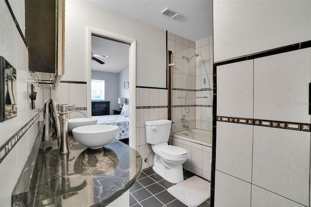 ensuite bathroom featuring toilet, a sink, tiled shower / bath, ensuite bath, and visible vents
