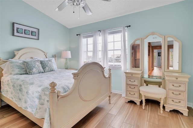 bedroom featuring baseboards, lofted ceiling, a textured ceiling, and light wood-style flooring