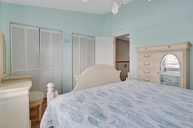 bedroom with a towering ceiling, multiple closets, visible vents, and ceiling fan