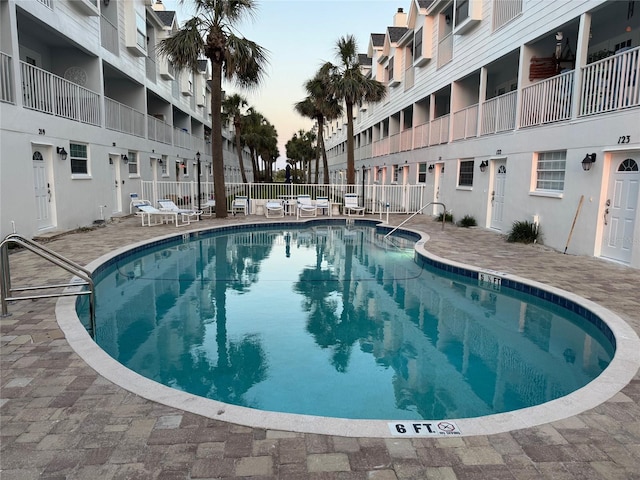 community pool with a patio area and fence