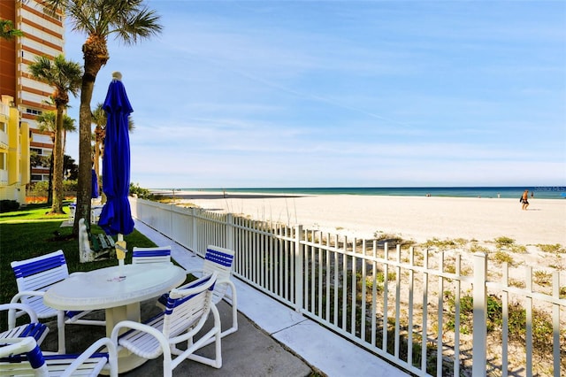 exterior space with a view of the beach, outdoor dining space, and a water view