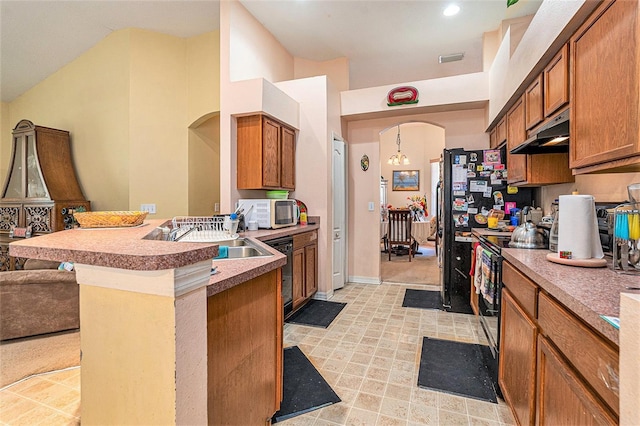 6130 Whimbrelwood Dr, Lithia, FL 33547 - kitchen featuring brown cabinetry, under cabinet range hood, a peninsula, and black appliances