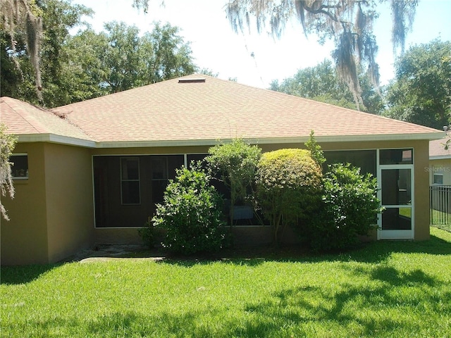 6130 Whimbrelwood Dr, Lithia, FL 33547 - back of house featuring stucco siding, a sunroom, a lawn, and a shingled roof