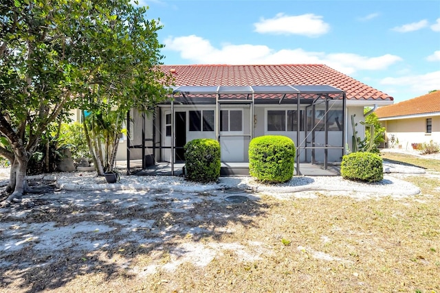 1969 Wolf Laurel Dr, Sun City Center, FL 33573 - back of property featuring a tiled roof, glass enclosure, stucco siding, and a patio area