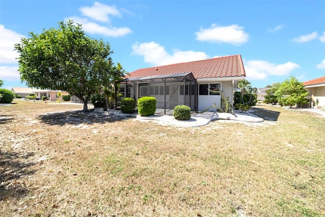 1969 Wolf Laurel Dr, Sun City Center, FL 33573 - back of property with stucco siding, a tiled roof, a lawn, and glass enclosure