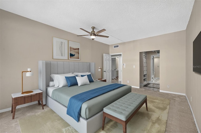 bedroom with a ceiling fan, visible vents, light carpet, baseboards, and a textured ceiling