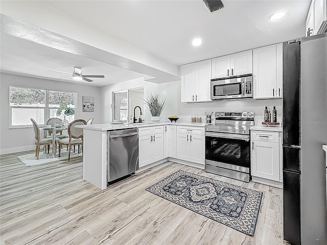1469 S Hillcrest Ave, Clearwater, FL 33756 - kitchen featuring stainless steel appliances, light countertops, a peninsula, white cabinets, and a ceiling fan