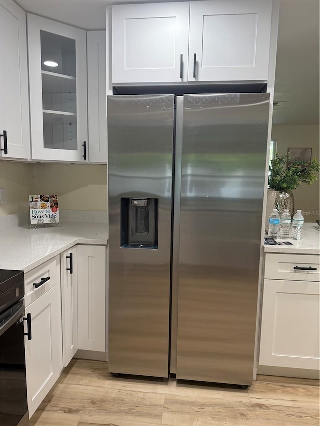 1469 S Hillcrest Ave, Clearwater, FL 33756 - kitchen with stainless steel refrigerator with ice dispenser, white cabinetry, light wood finished floors, glass insert cabinets, and stove