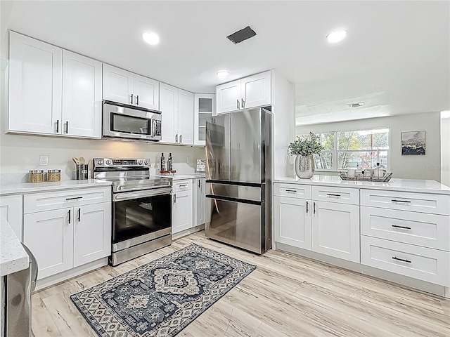 1469 S Hillcrest Ave, Clearwater, FL 33756 - kitchen featuring stainless steel appliances, white cabinets, light wood finished floors, recessed lighting, and glass insert cabinets