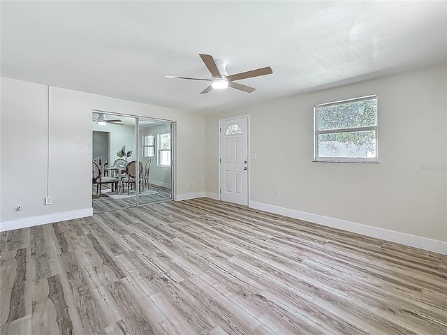 1469 S Hillcrest Ave, Clearwater, FL 33756 - unfurnished living room with light wood-style flooring, a ceiling fan, and baseboards