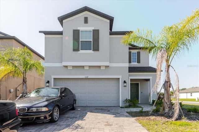 traditional-style house featuring decorative driveway, a garage, and stucco siding