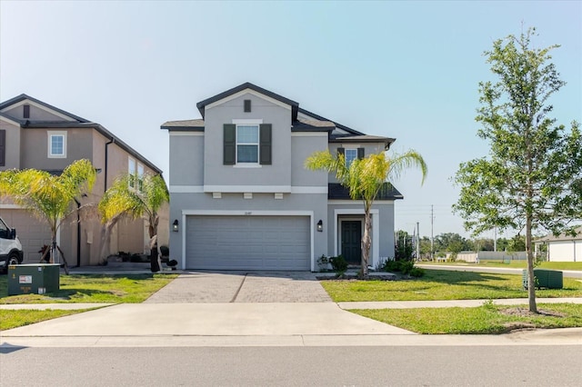 traditional home featuring a front yard, driveway, stucco siding, and an attached garage
