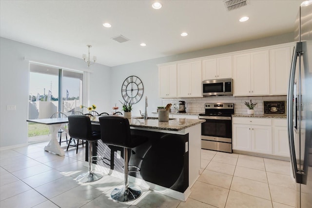 kitchen with tasteful backsplash, visible vents, appliances with stainless steel finishes, and light stone countertops