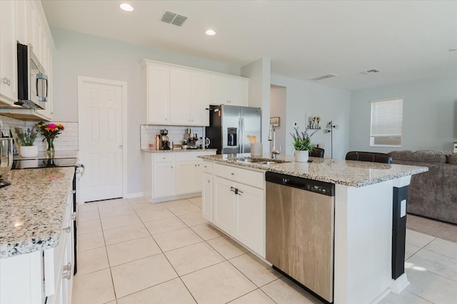 kitchen with visible vents, light tile patterned floors, open floor plan, stainless steel appliances, and backsplash
