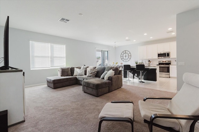 living room with baseboards, an inviting chandelier, recessed lighting, visible vents, and light colored carpet