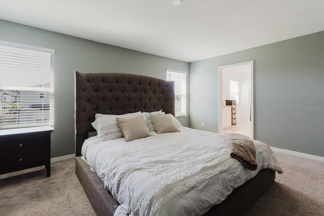 carpeted bedroom with ensuite bathroom and baseboards